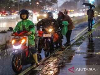 Sejumlah pengendara motor berhenti untuk memakai jas hujan. ANTARA