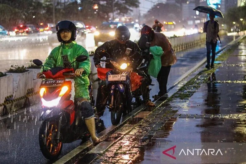 Sejumlah pengendara motor berhenti untuk memakai jas hujan. ANTARA